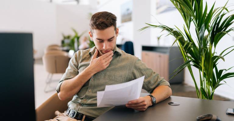 Portret van een gefocuste mannelijke klant die het contract voor de aankoop van onroerend goed leest.